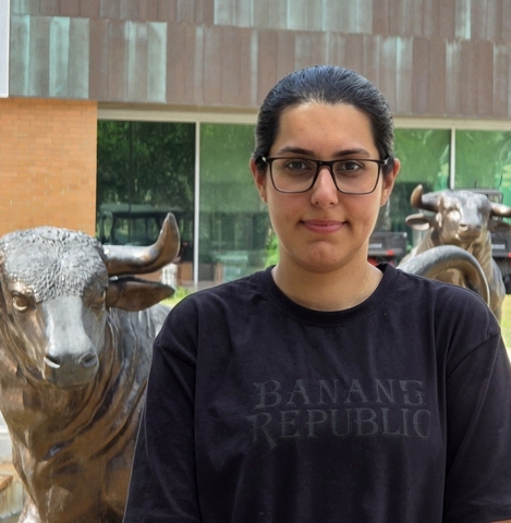 Woman in glasses stands next to bronze bull statue with "Banana Republic" shirt.